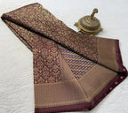 Folded brown and gold patterned fabric with a decorative metal object on a white background