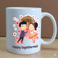 White mug with a cartoon illustration of a couple holding an umbrella and hearts, with the text 'happy togetherness' on a brown background.