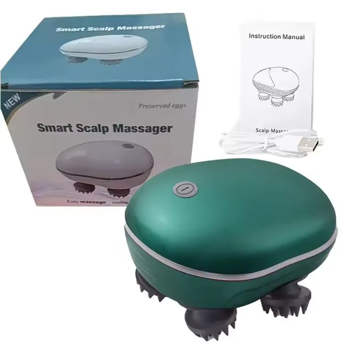 A smart scalp massager shown with its retail box, instruction manual, and charging cable on a white background. The massager itself is oval-shaped with a dark teal-green body, a silver button on top, and dark gray massage spikes on the bottom.