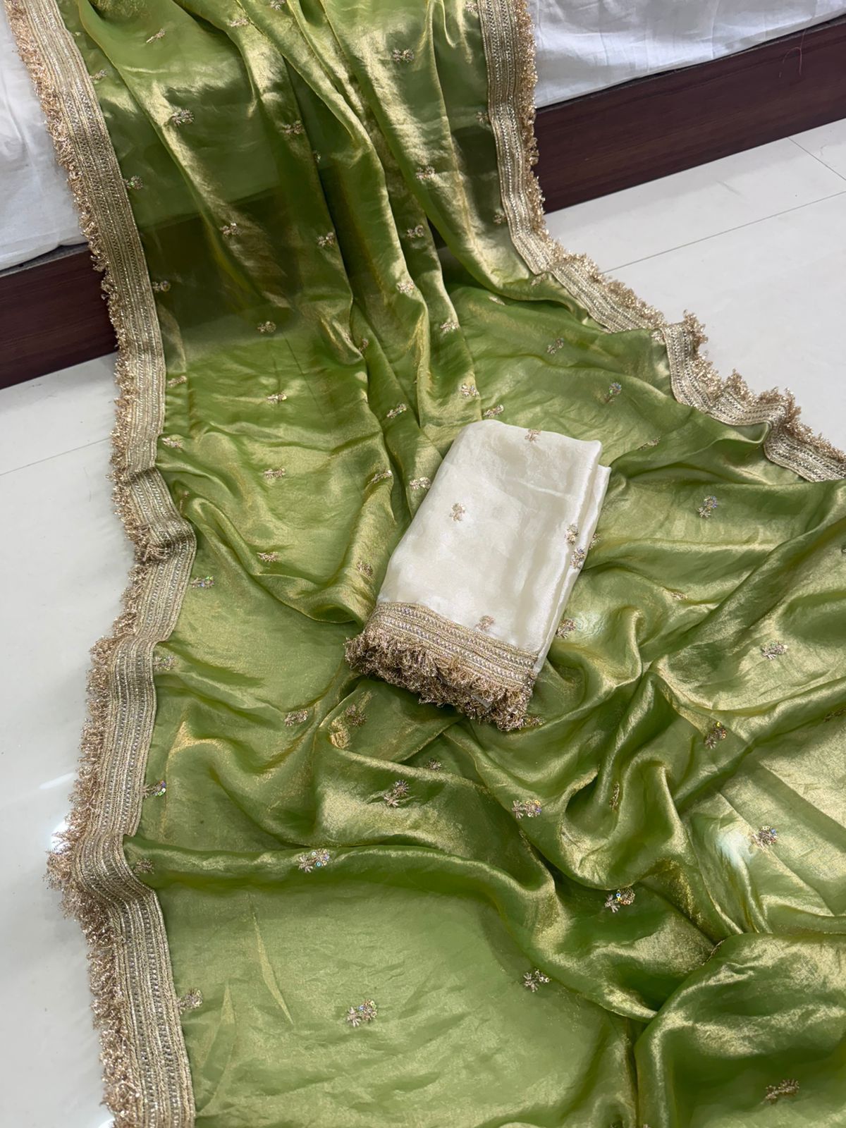 Green fabric with gold border and white cloth on a white surface