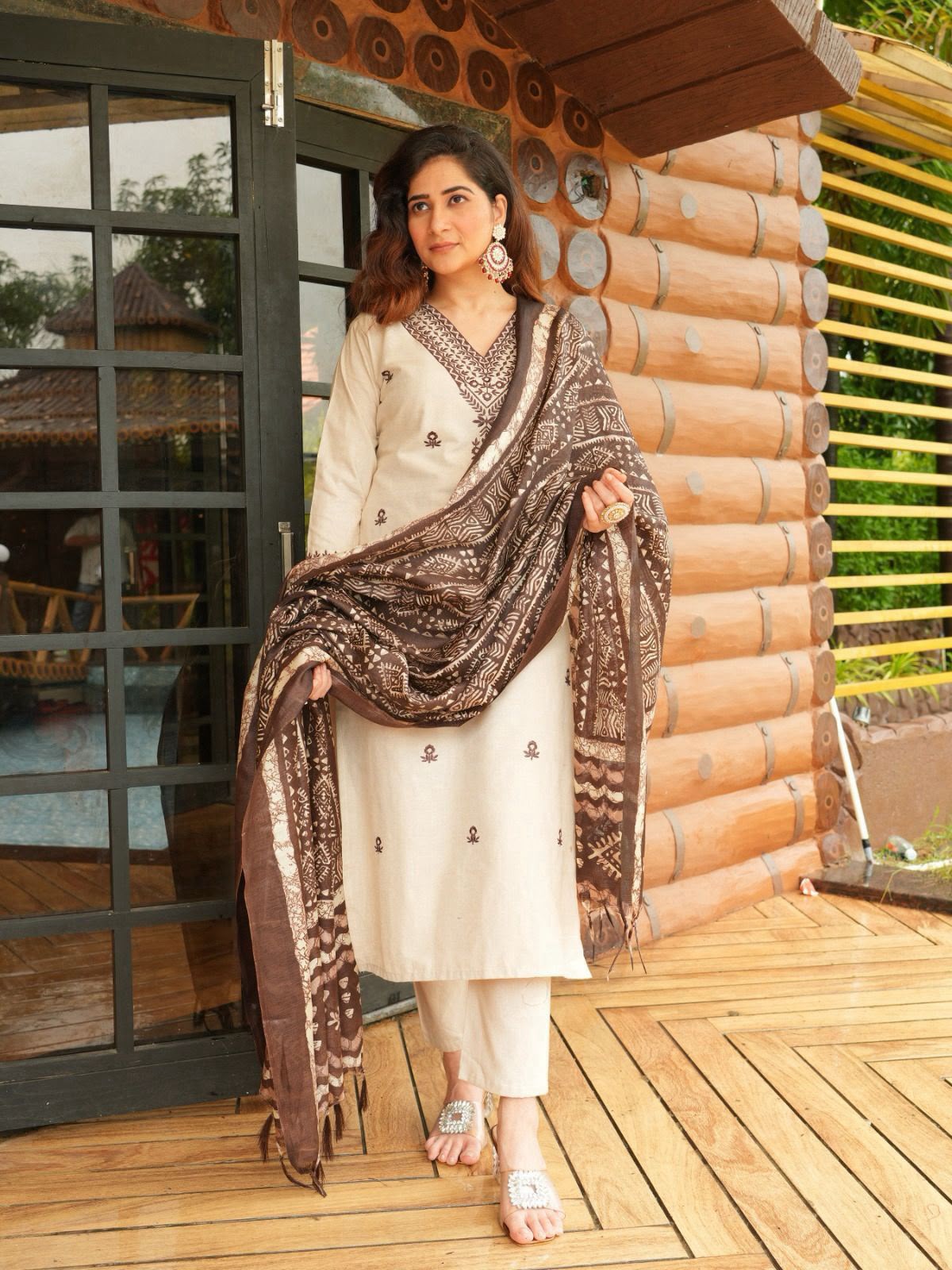 Woman in traditional attire standing on a wooden deck with a rustic background