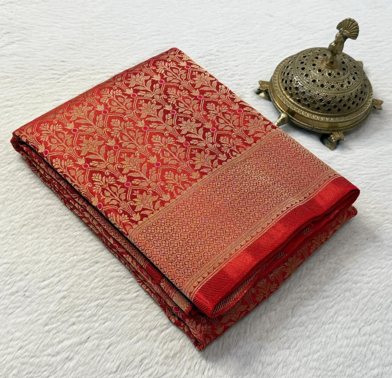 Folded red fabric with gold patterns next to a brass incense burner on a white background