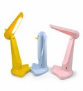 Three modern adjustable desk lamps in yellow, light blue, and pink, arranged side by side on a plain white background.