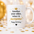 White mug with birthday message on a festive background with gold confetti and balloons.
