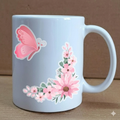 White mug with pink butterfly and floral design on a wooden surface.