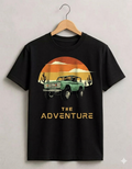 Black t-shirt with a graphic of a vintage truck and sunset design, hanging on a wooden hanger against a light gray background.