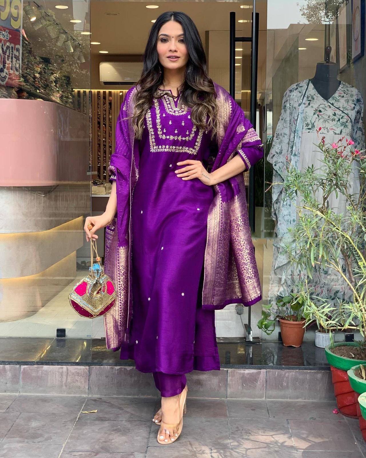 Woman in a purple traditional outfit standing in front of a store entrance.