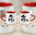 Two white mugs with red interiors and handles, one labeled 'Mr.' and the other 'Mrs.', on a wooden surface.