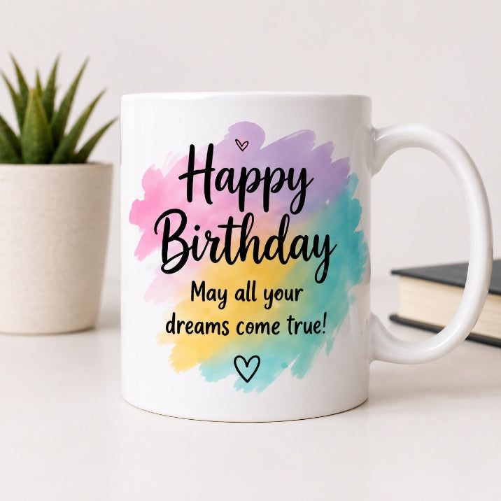 White mug with colorful watercolor design and birthday message on a light surface.