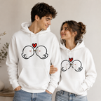 Two people wearing white hoodies with a heart and glasses design, standing close together.